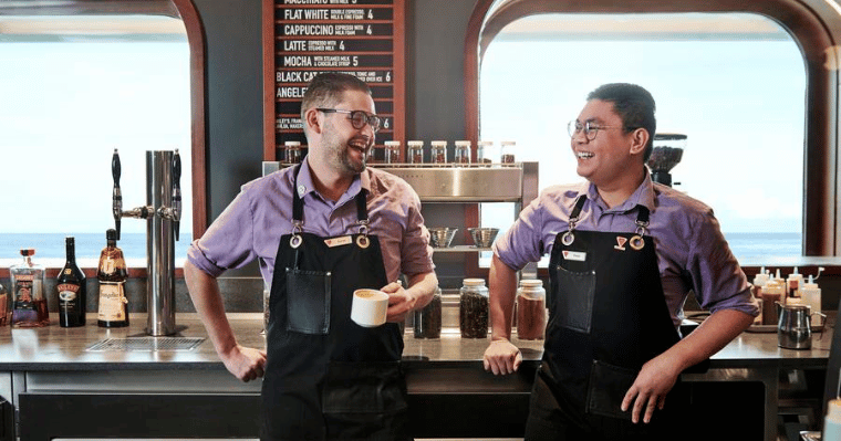 Two baristas smile and laugh while working at Grounds Club cafe
