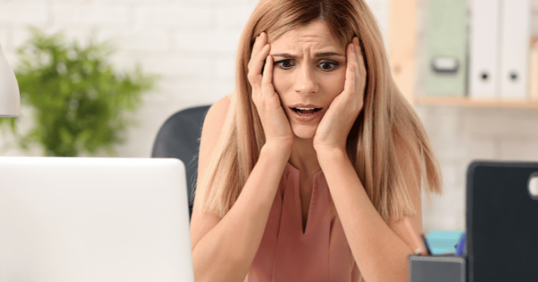 A woman is fedup and holding her head in front of a laptop